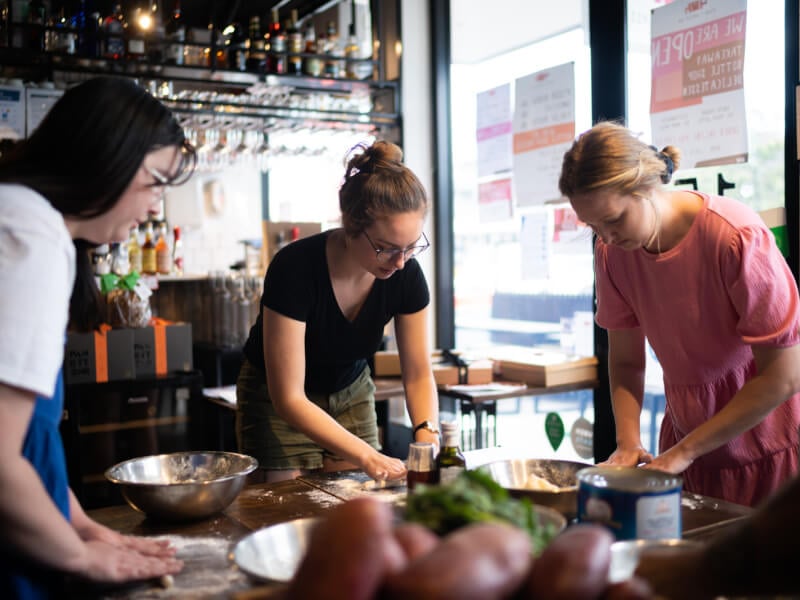 Three friends make pasta dough at a pasta making class in Brisbane