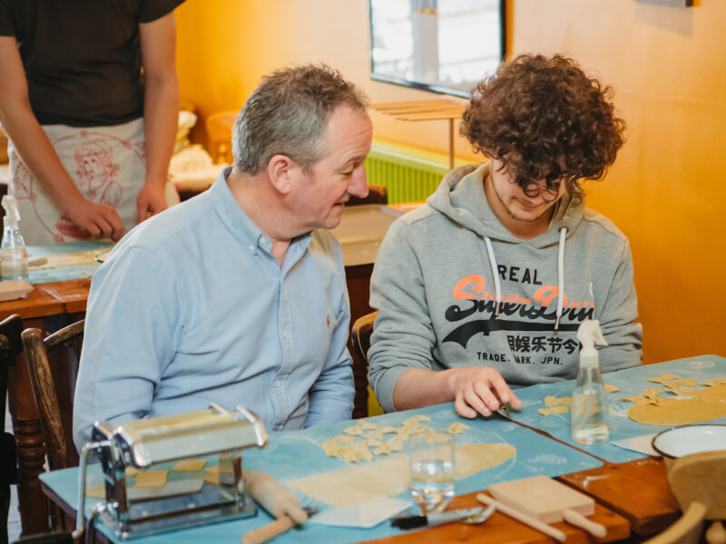 Father and son making pasta together at a workshop