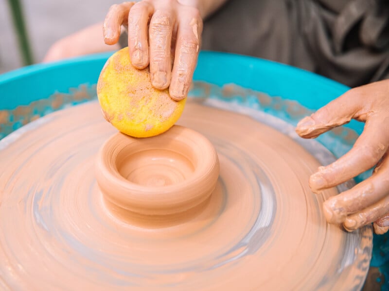 Person using sponge at a wheel throwing class
