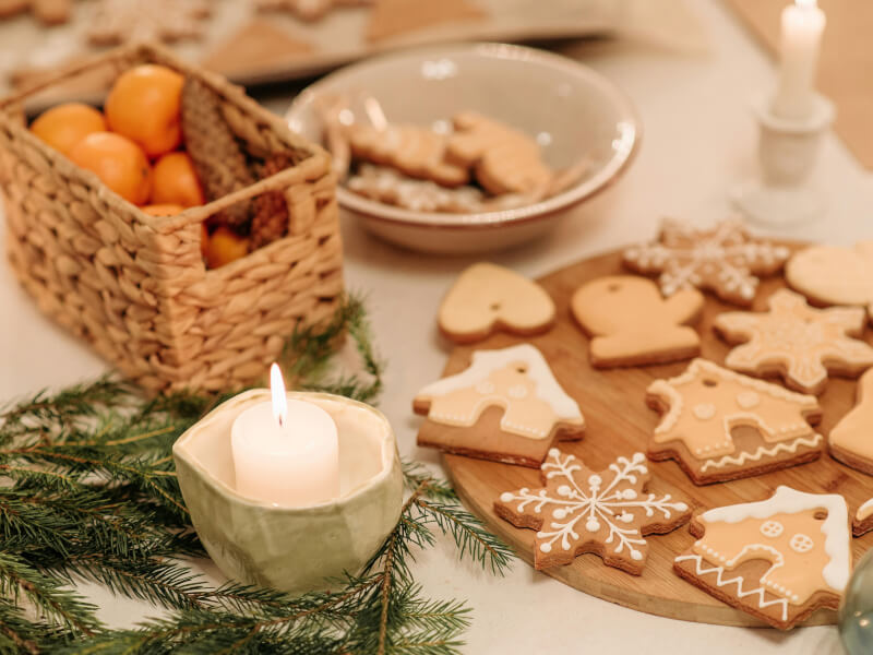 Christmas cookies on a wooden serving platter next to a candle 