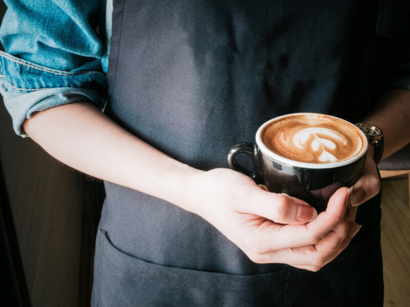 A woman cradles a mug of coffee with heart shaped latte art