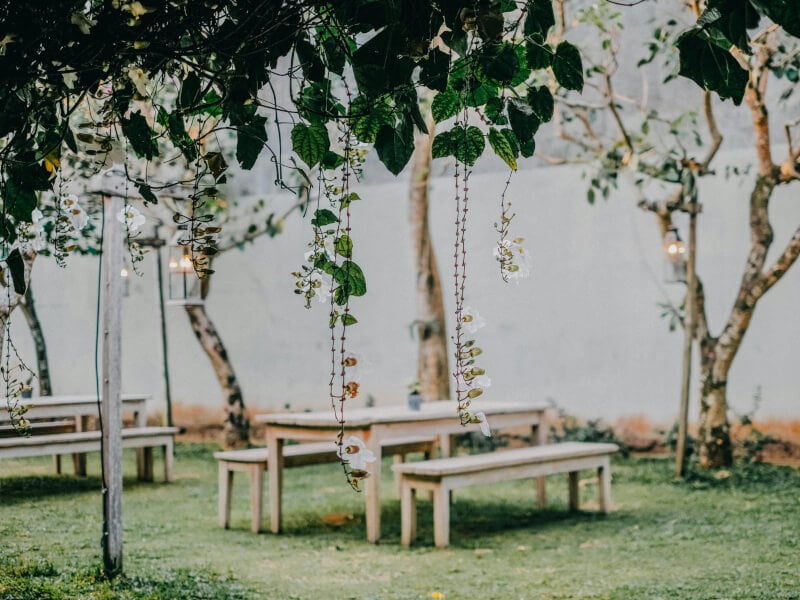 Table and benches set up in garden with some hanging candles