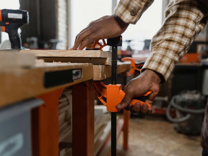 Man tightening a clamp onto a wooden bench