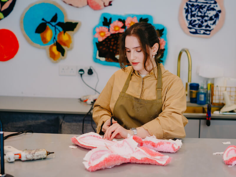 A woman tufting a unique rug at a textile class in Brisbane