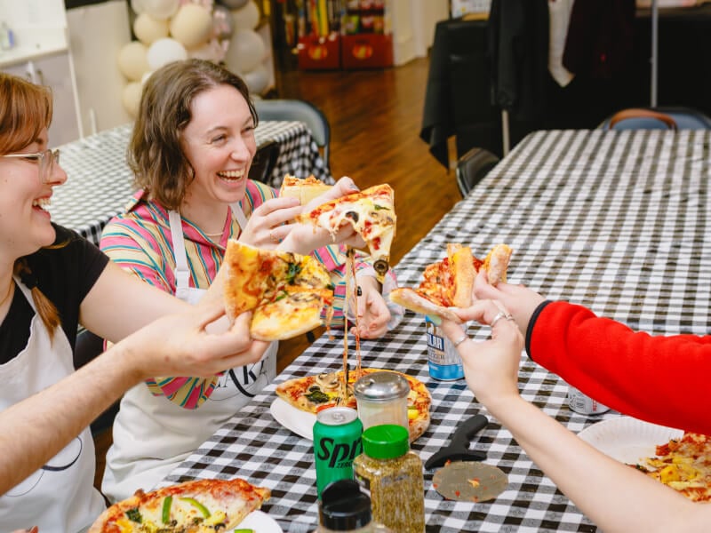 A group of friends eat the pizza they made at a cooking class