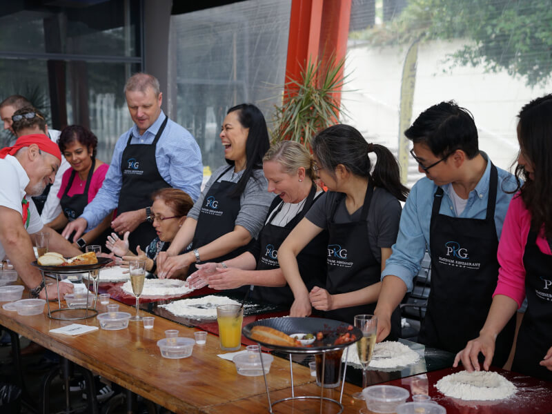 A group of colleagues make pizza for their team building activity