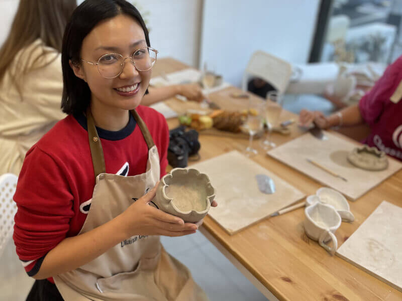 A woman poses with her finished pottery piece
