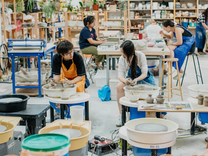 A couple making pottery at a wheel throwing class