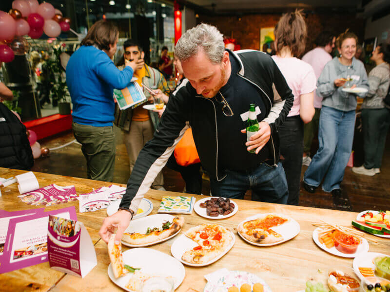 A man reaching for pizza at a birthday party