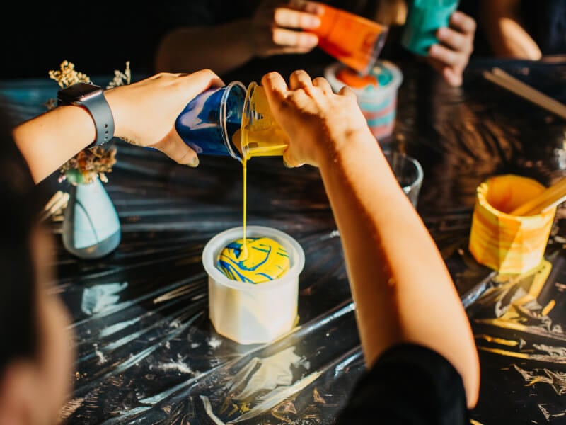 Person pouring colourful paints at fluid art class