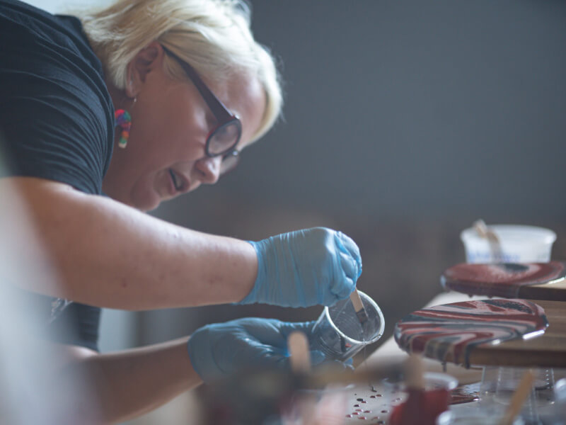 Woman decorating wooden board with resin