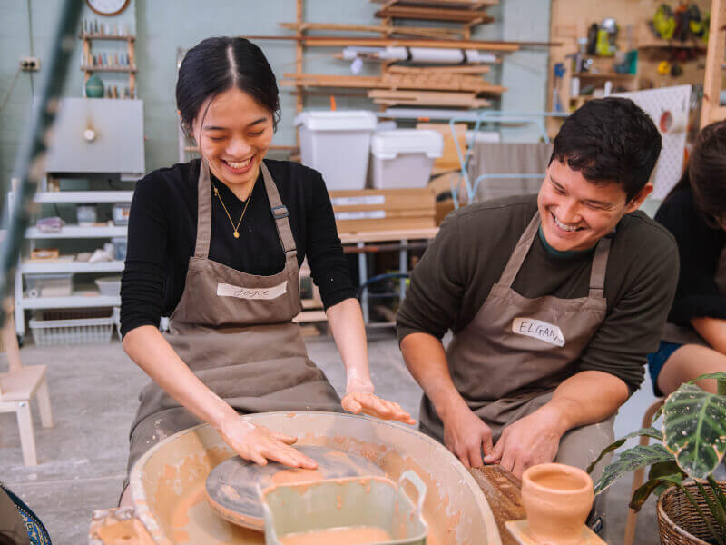 A couple laughs while making pottery on the wheel