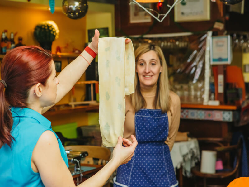 Cooking teacher showing handmade pasta dough to cooking class student
