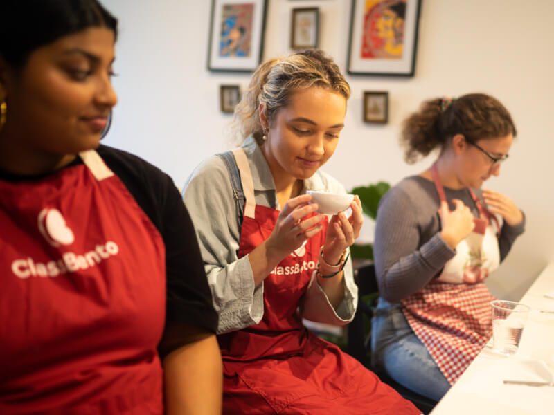 Three women smelling spices at an Indian cooking class