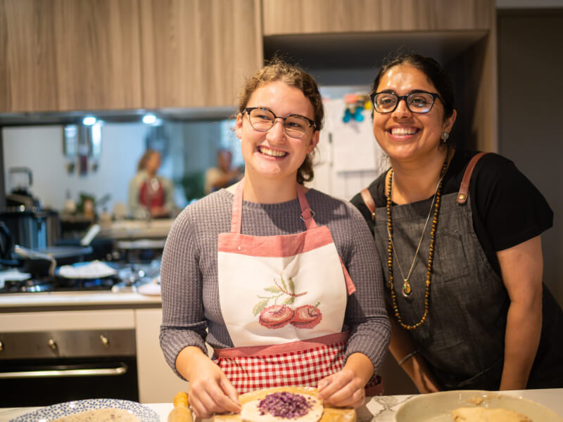 Two women smiling at a cooking class they're doing together