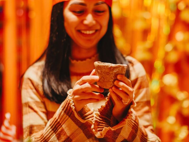A woman smiling and holding a rough handmade mug