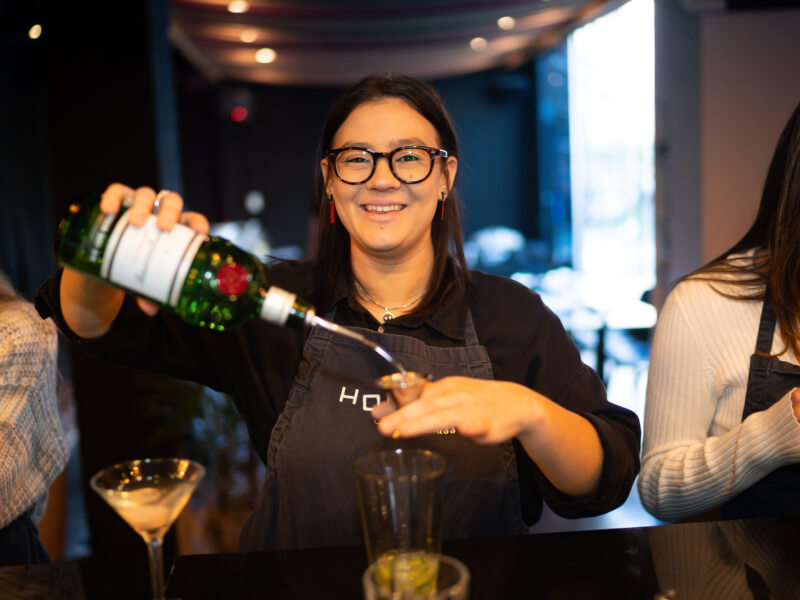 A woman pouring liquor into a nipper at a cocktail class