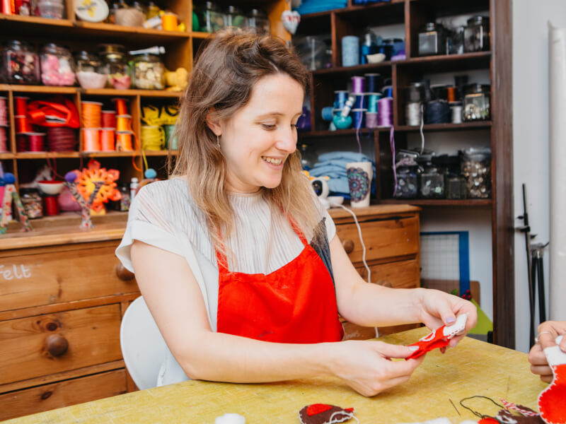 A woman smiling while she sews at a sewing class