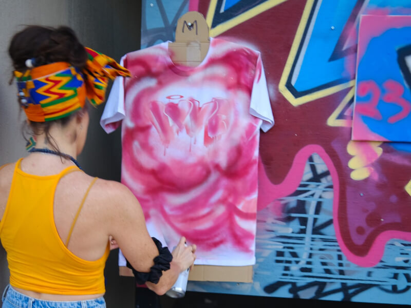 A woman spray painting a tshirt