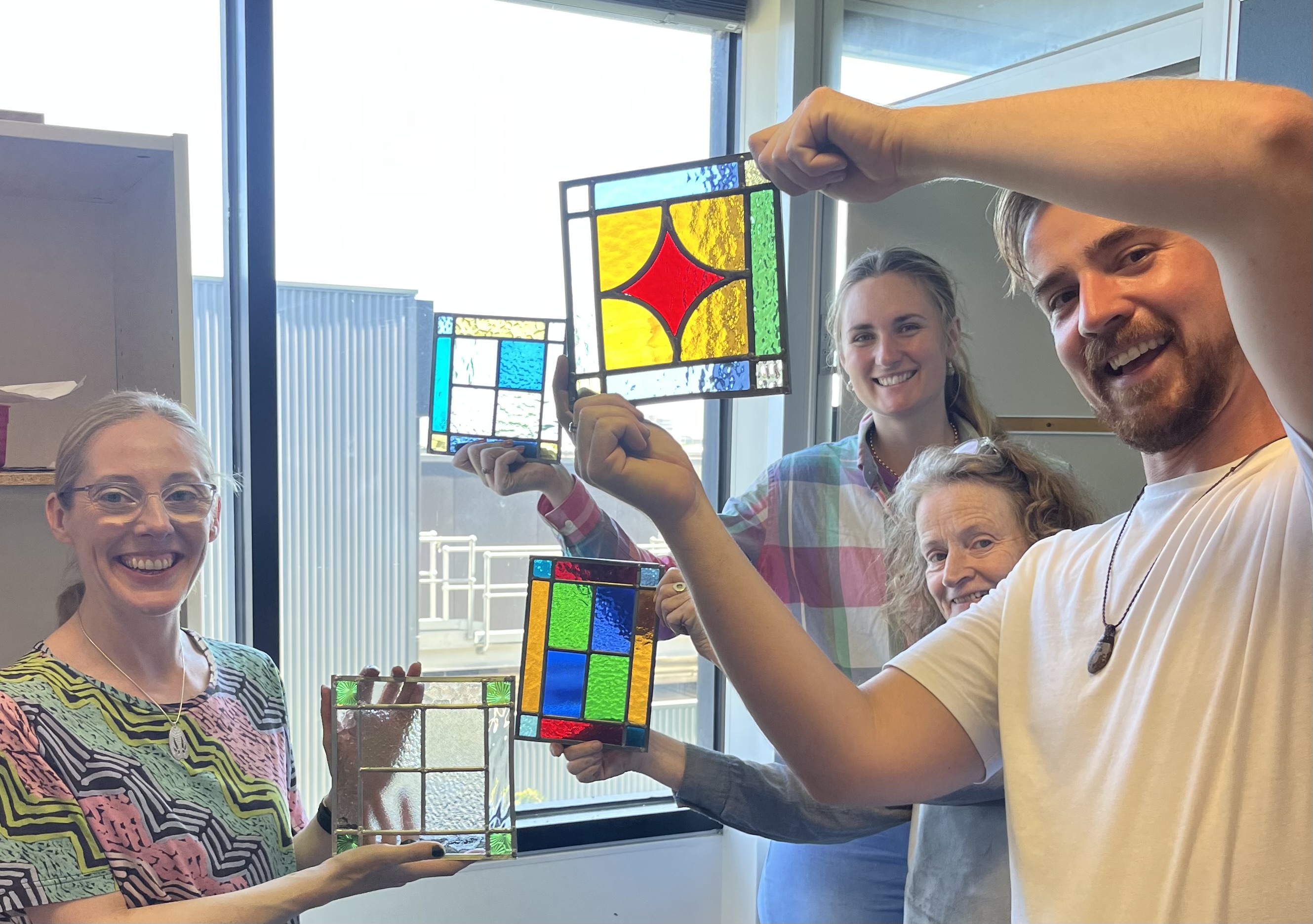 People showing off their stained glass pieces