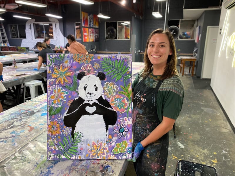 Woman posing with her finished painting at an art class in Brisbane