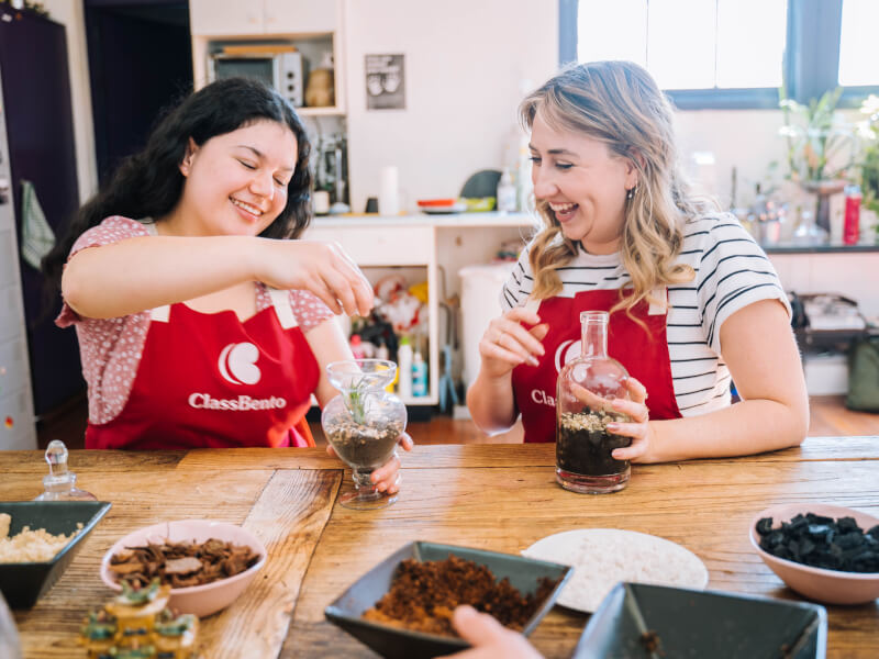 Two women smiling and making terrariums