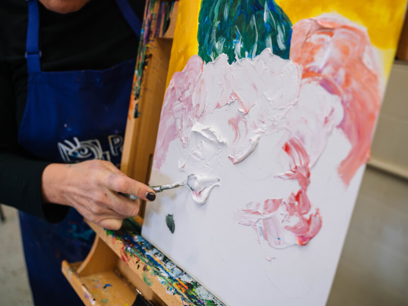 Hand working palette knife over textured paint canvas