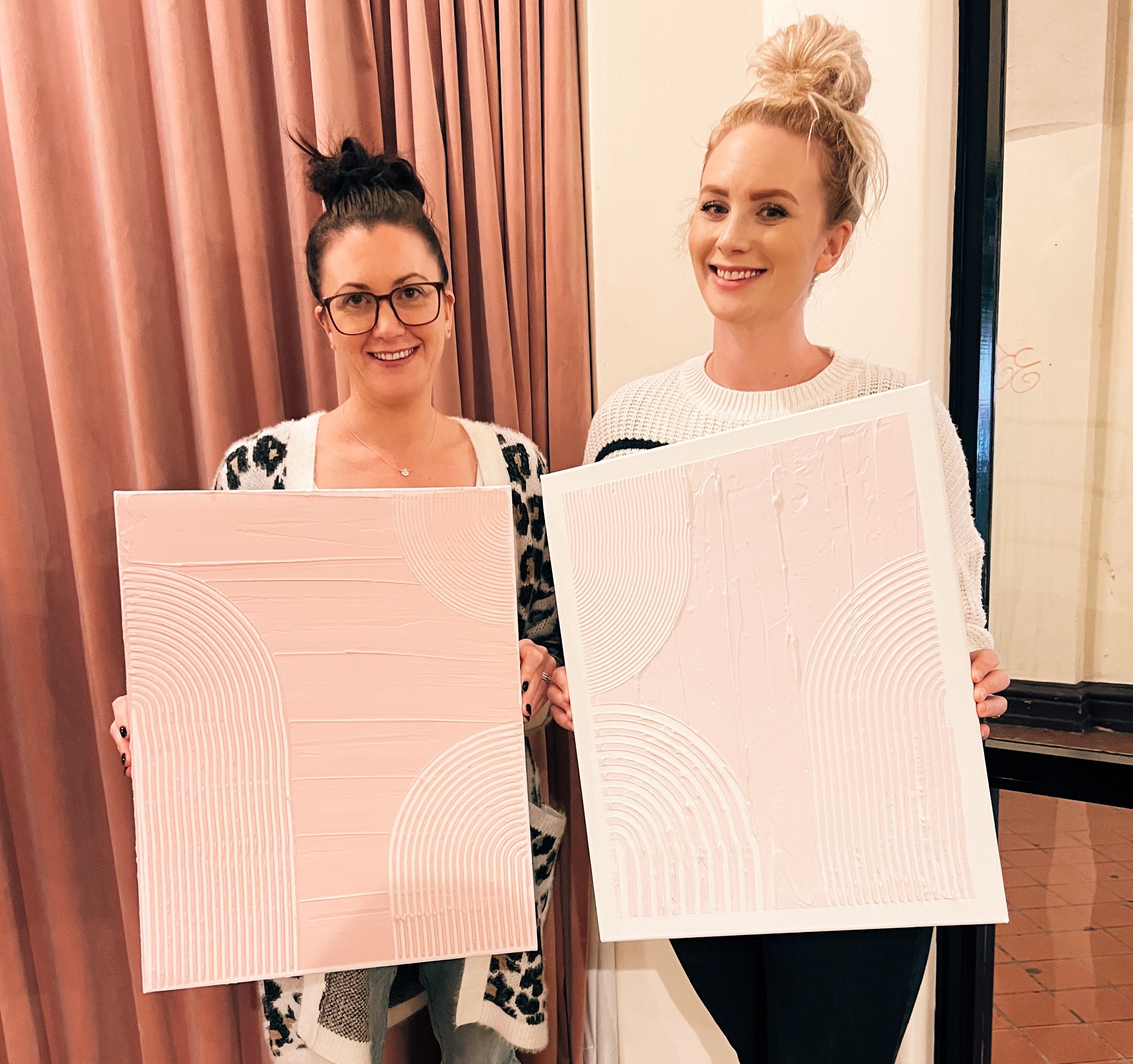 Women smiling and holding up their textured canvases