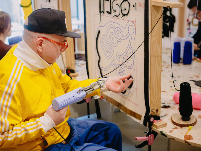 A man tufting a rug at a workshop
