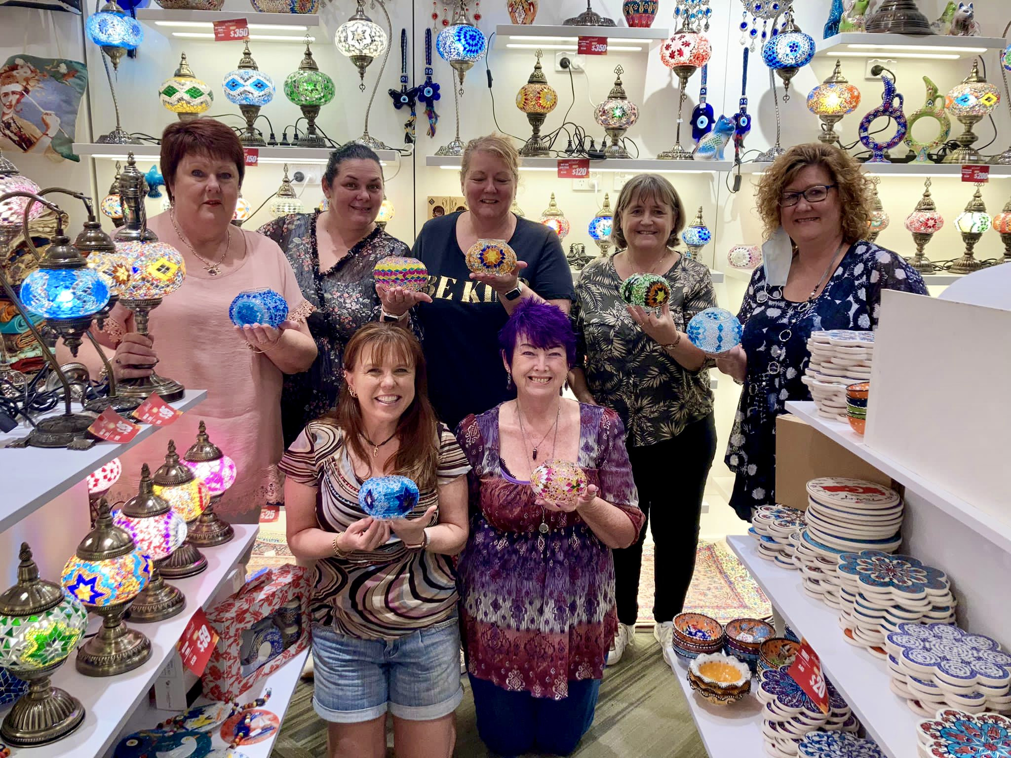 Women showing off their handmade Turkish mosaic lamps