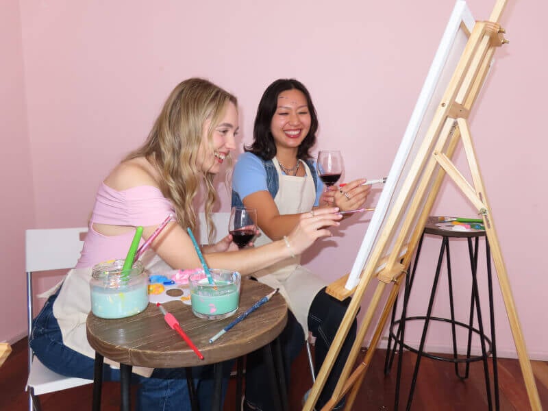 Two friends paint one canvas at a paint and sip class