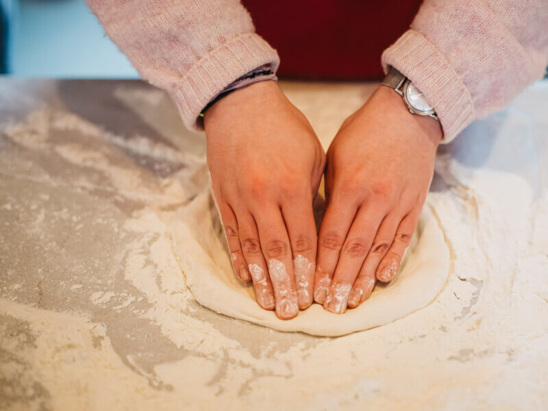 two hands making pizza dough