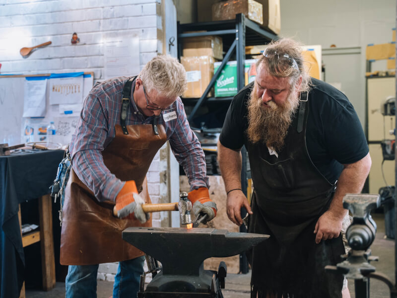 Two men having fun at a blacksmithing class