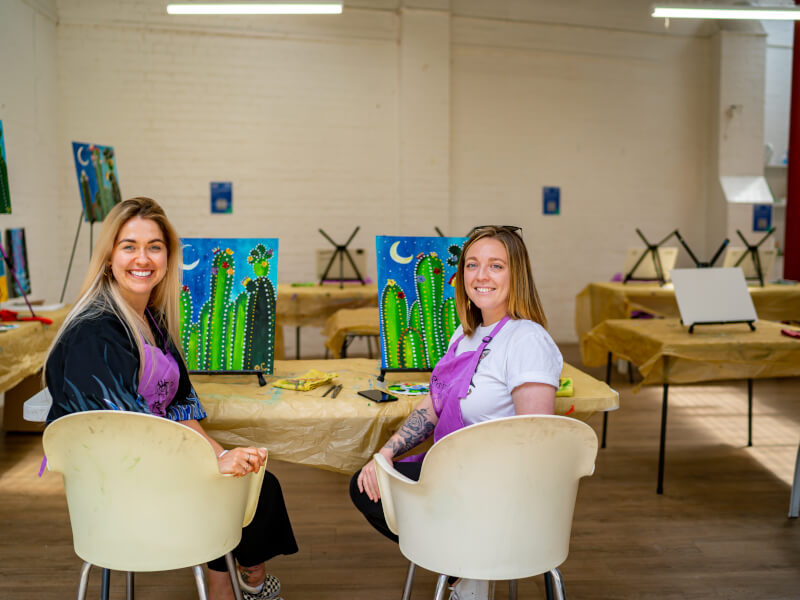 Couple showing their finished paintings at a paint and sip class for couples