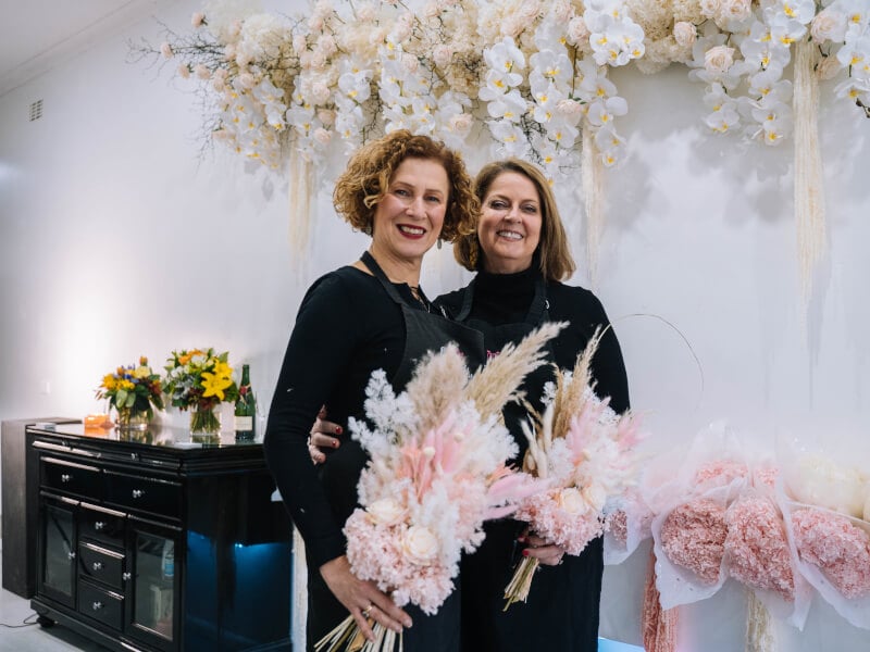 Two women hold their finished dried flower arrangements