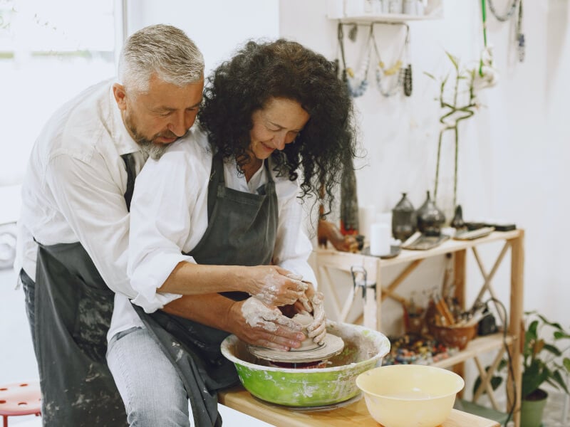 A couple at the wheel throwing clay