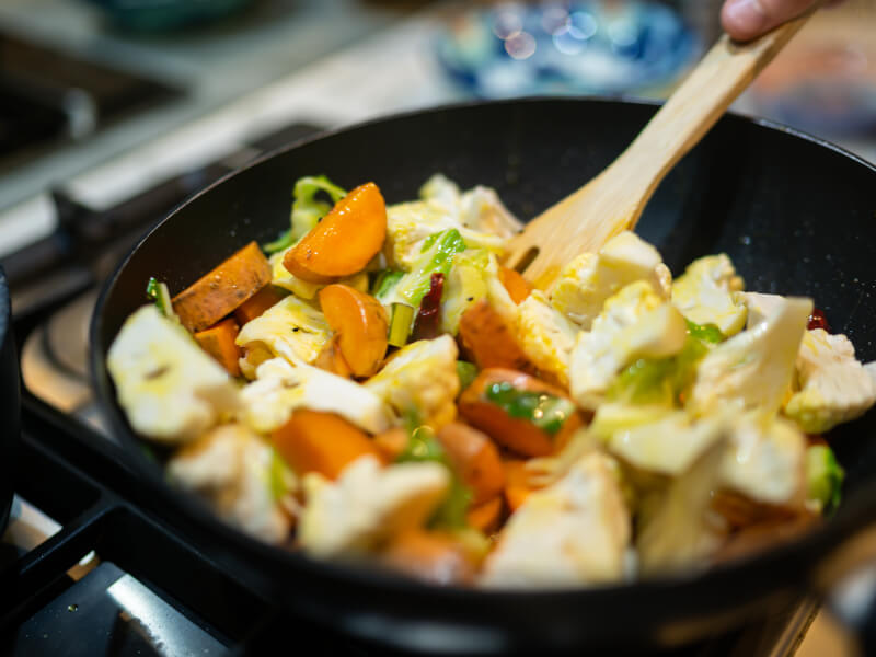 Vegan meal with sweet potato and cauliflower being cooked in pan