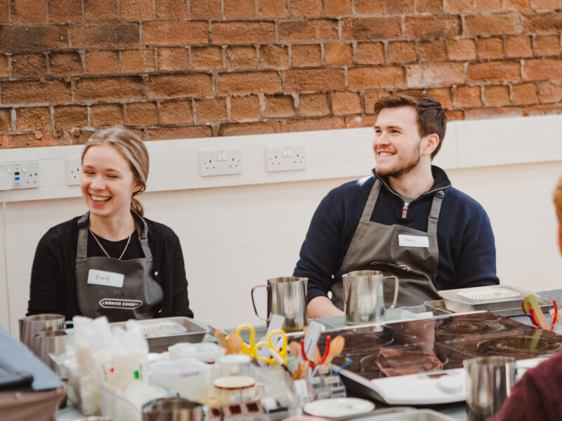 A woman and man smiling at a candle making class