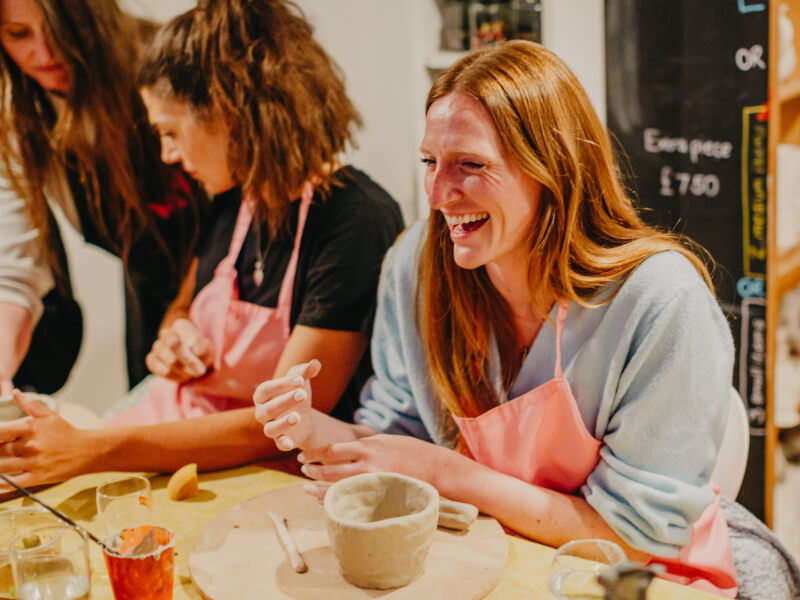 A woman smiling at a pottery class