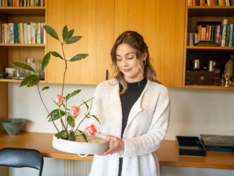 Woman smiling while holding up Ikebana