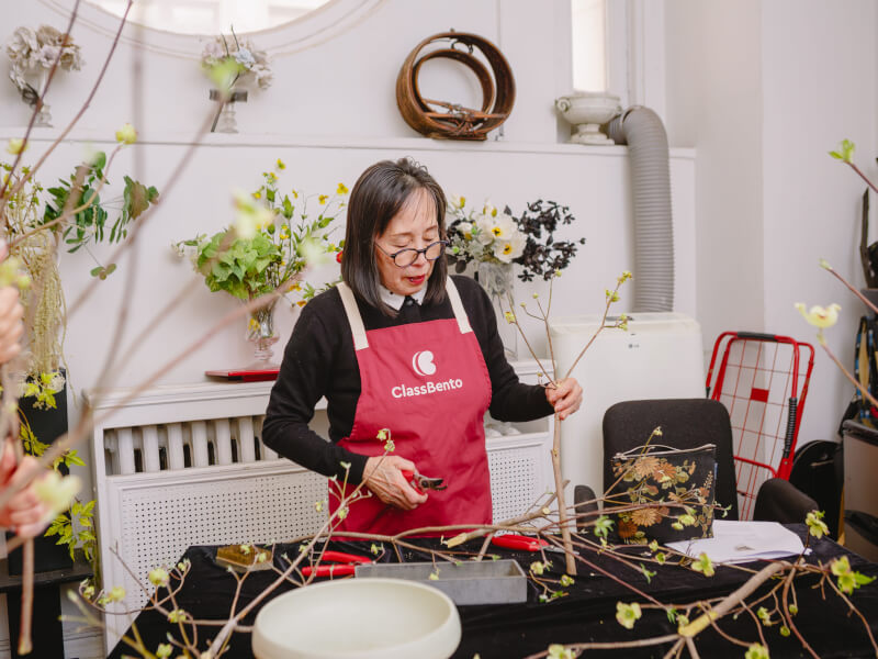 A woman surrounded by flowers at an ikebana class
