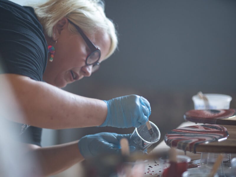 A mother focused on pouring paint at a fluid art class