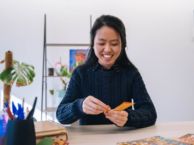 A woman smiles while folding origami at a Mother's Day workshop