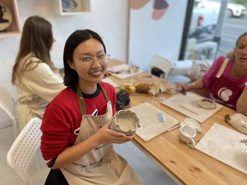Woman holds her handmade clay mug while smiling