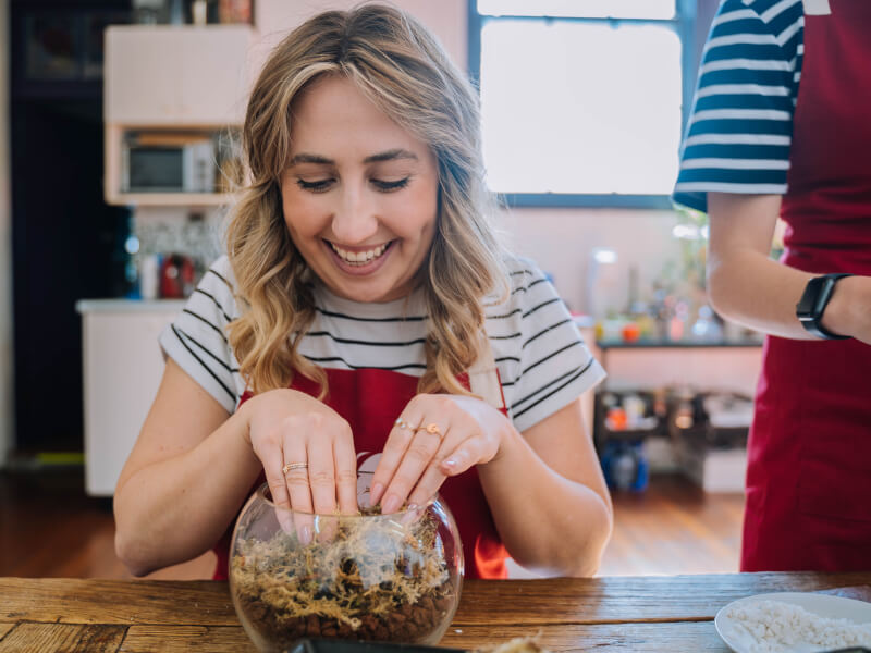 A woman delights in building a terrarium with her hands