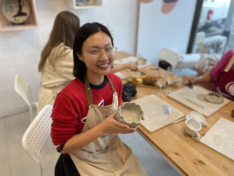 A happy woman holding the mug she made at a mug making workshop