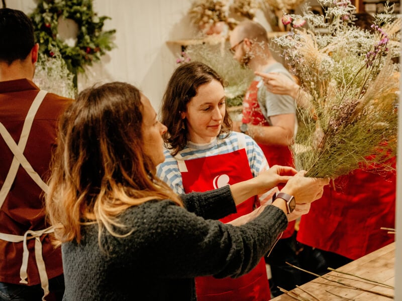 A smiling woman looks at ease at a floristry class