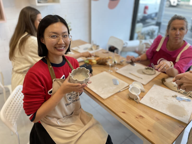 A woman smiles with her handmade pottery