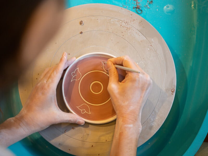 Women carving out designs on ceramics