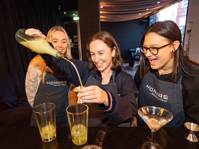 Teammates laugh as they make cocktails